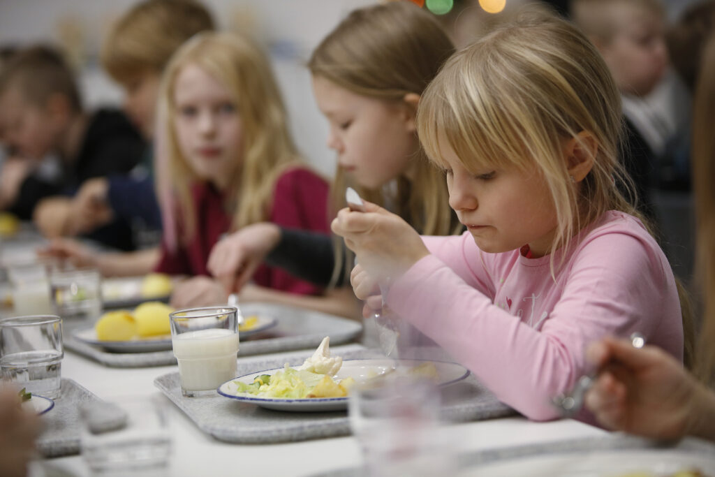 Lapset ruokailevat koulun ruokasalilla.