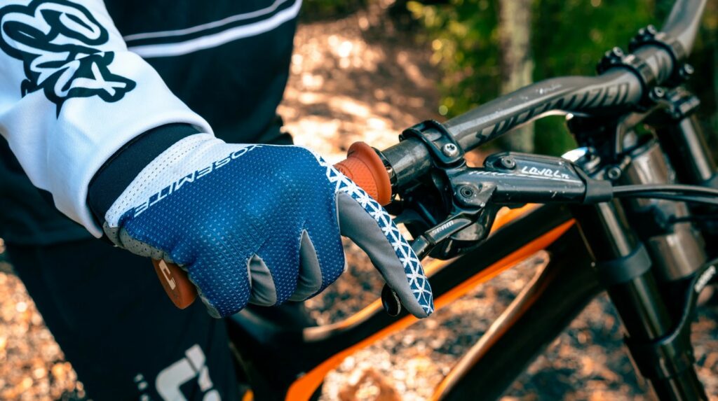 Käsi pitää kiinni pyörän ohjaustangosta. Käteen on puettu pyöräilyhanska.