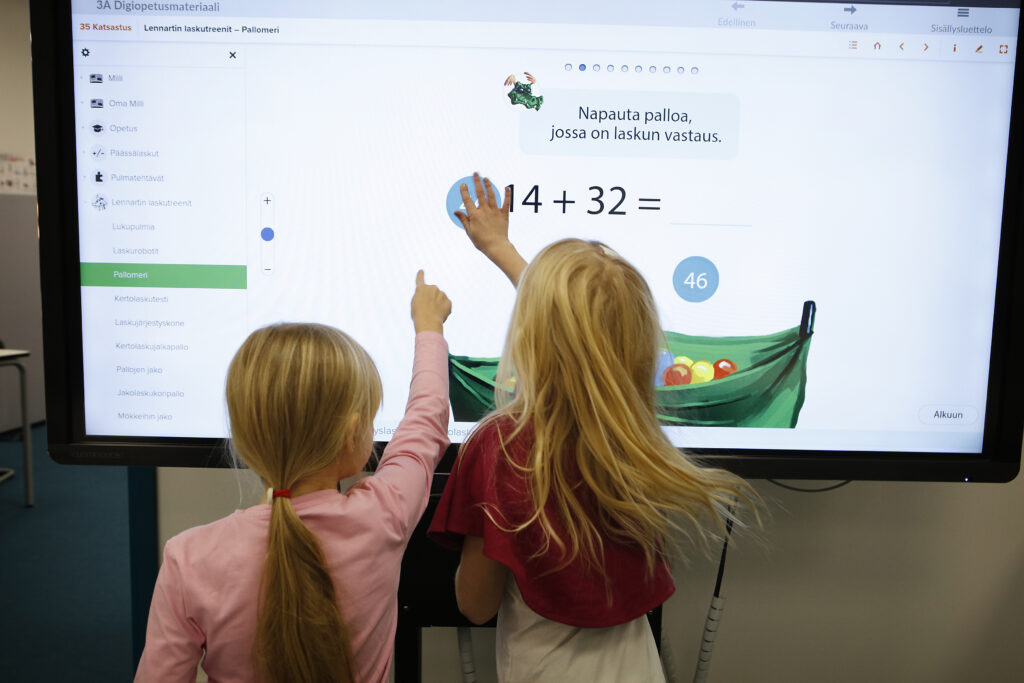 kaksi lasta käyttävät digitaalista näyttöä koulussa.