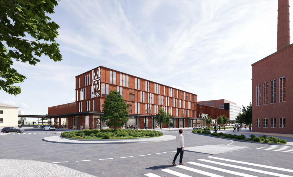 Havainnekuva: Näkymä Eteläisen Asemakadun ja Paloheimonkadun kiertoliittymältä kohti uutta HAMKin kampusta. Rakennus kohoaa etualalla nelikerroksisena, julkisivu on ruosteen väristä metallia ja ikkunapintaa. On lähes pilvetön kesäpäivä. Ihmisiä kuljeskelee katuympäristössä.