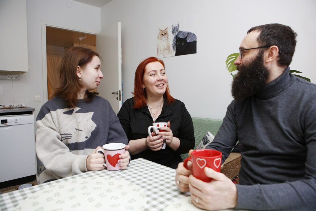 Perhe juttelemassa keittiön pöydän ääressä.