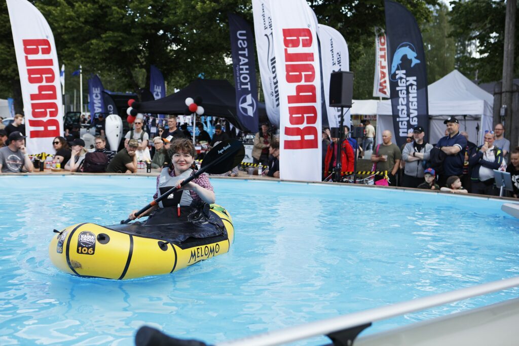 Nainen meloo muovisella ilmatäytteisellä kanootilla altaassa, joka on täynnä vettä,