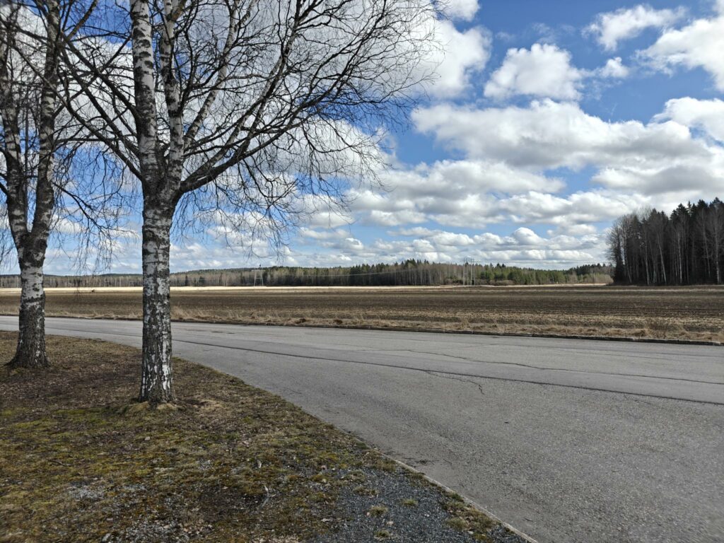 Edustalla asfaltoitu tie, jonka takana avoin peltoalue.