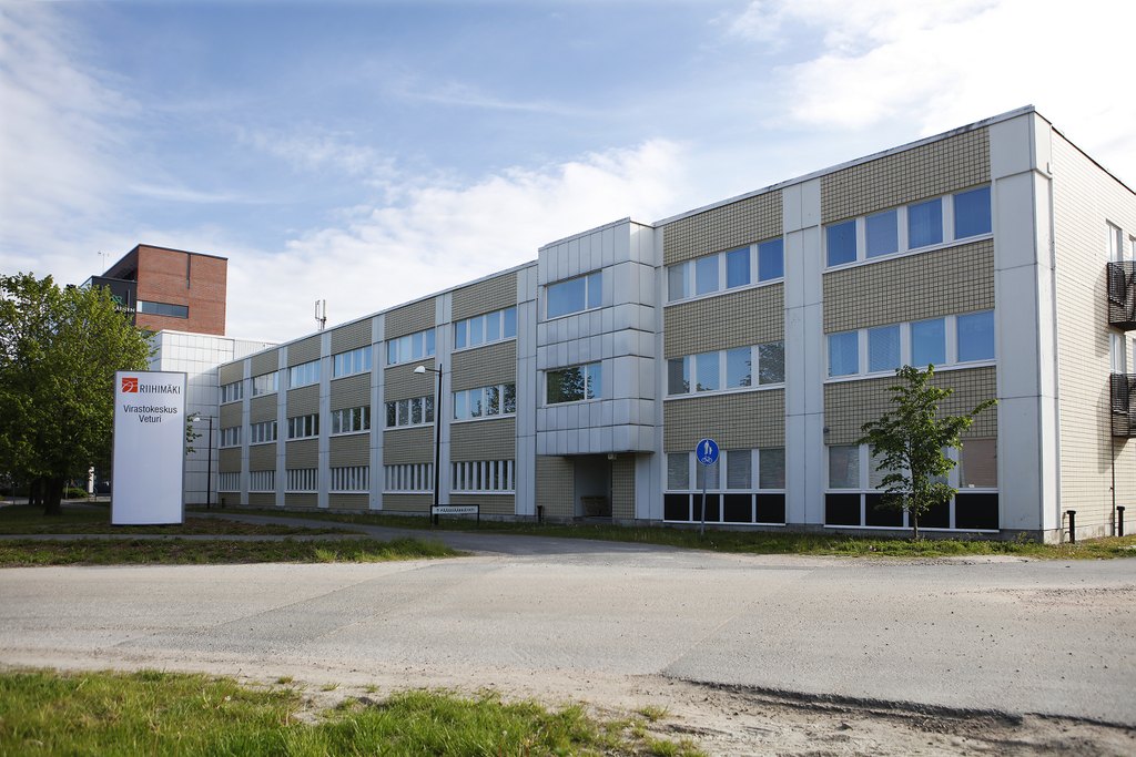 Vaalea kolmikerroksinen leveä toimistorakennus.
