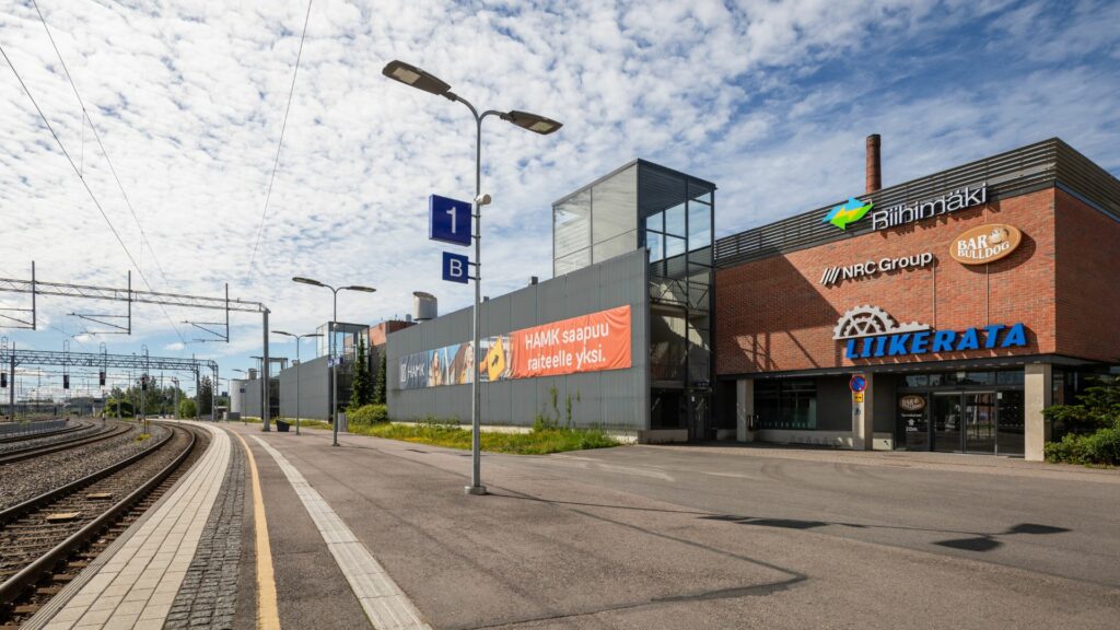 En stor låg kontorsbyggnad bredvid järnvägsplattformen.