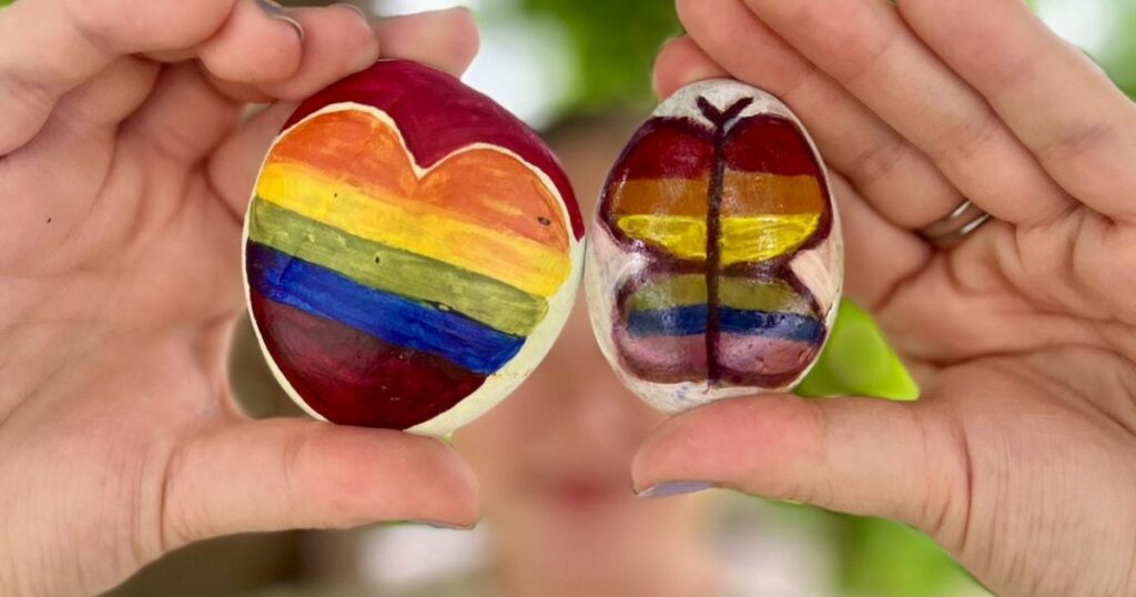prideaiheinen maalaus kahdessa kivessä, joita pidetään käsissä sormien välissä.