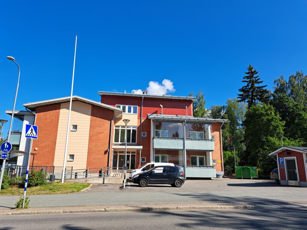 Kaksikerroksinen punertava rakennus.