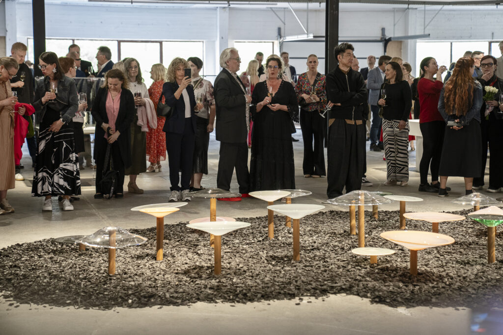 ihmisiä Riihimäen vanhalla lasitehtaalla Finnish Glass Biennale 2025 -näyttelyn avajaisissa.